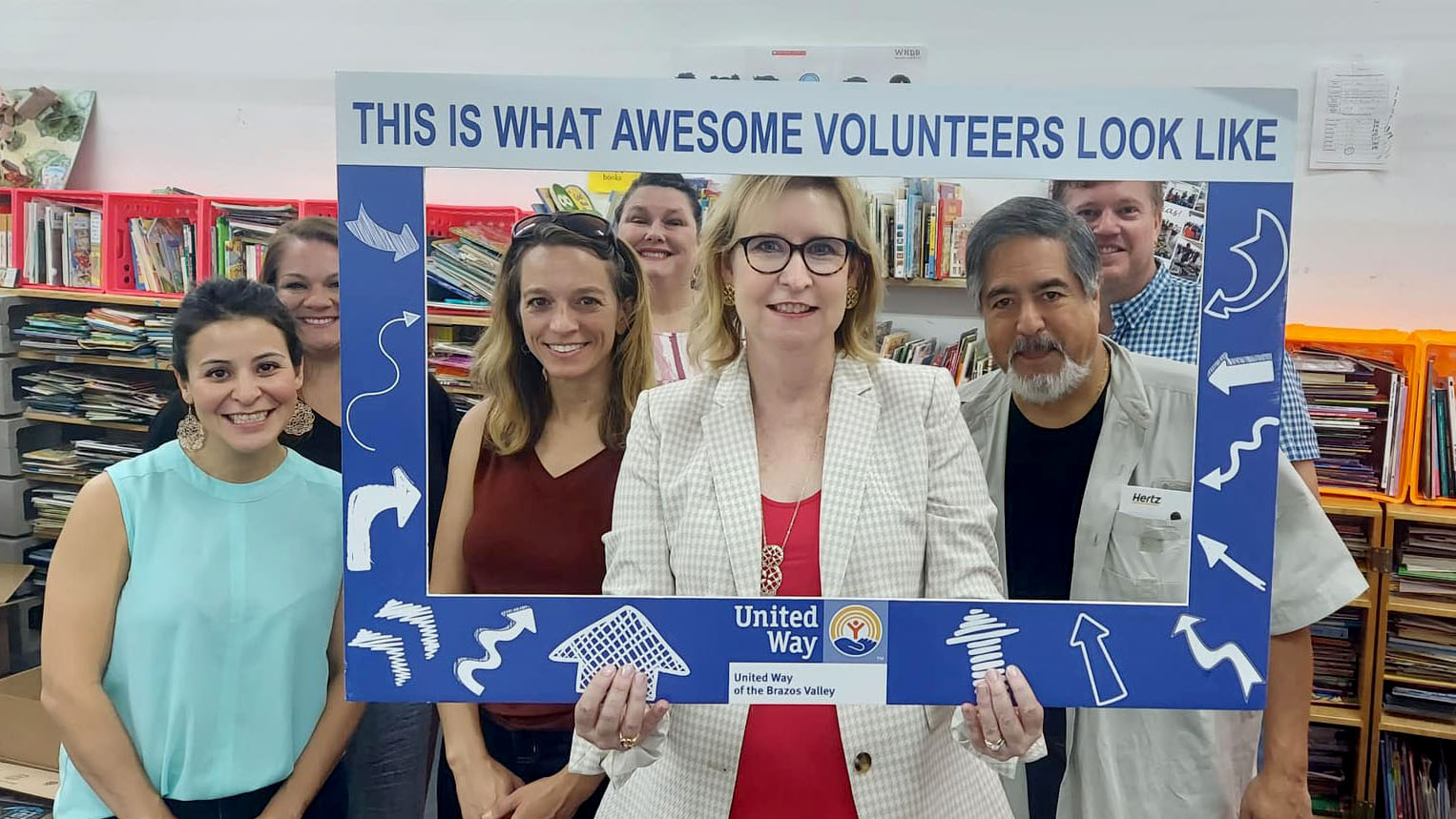 Six people pose behind a frame that reads: This is what awesome volunteers look like