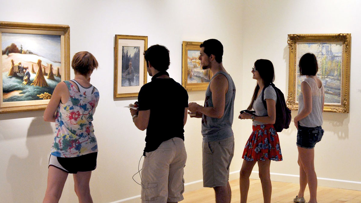 People observing paintings and sculptures in a gallery
