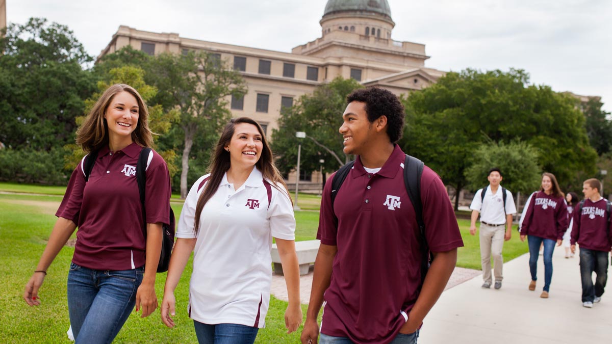 Three students dressed in maroon and white polos walking to class