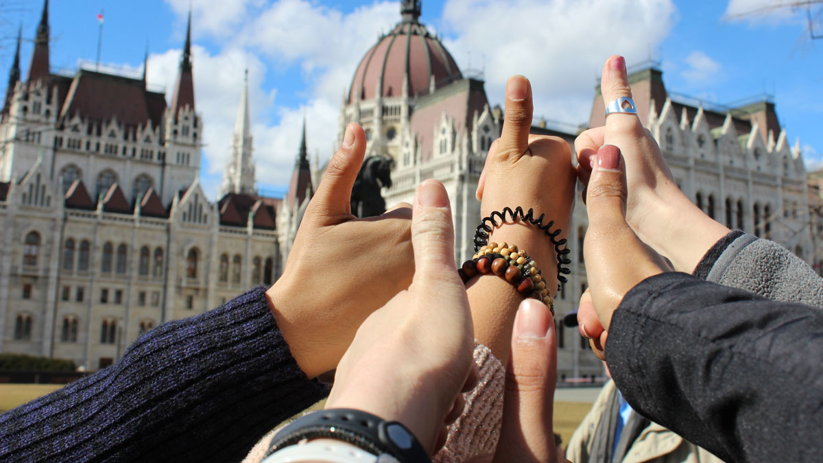 A group of hands giving a thumbs up in front of an ornate building