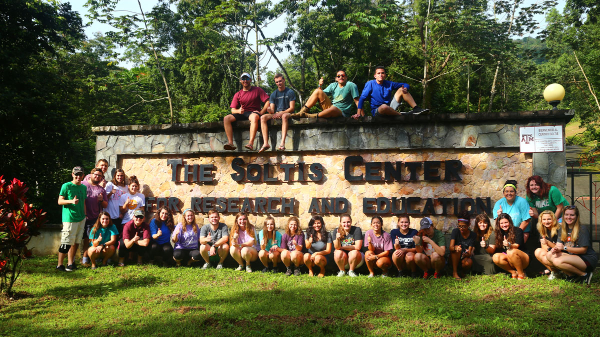 Students sitting around a sign that reads: The Soltis Center for Research and Education