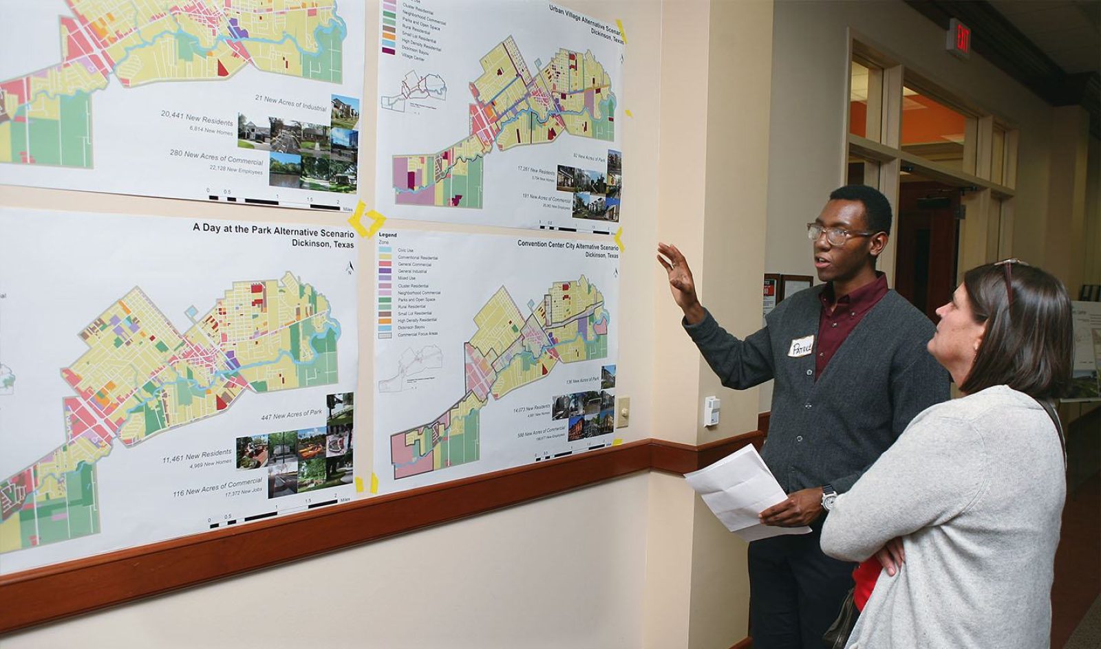 A student presents in front of a wall of park renderings